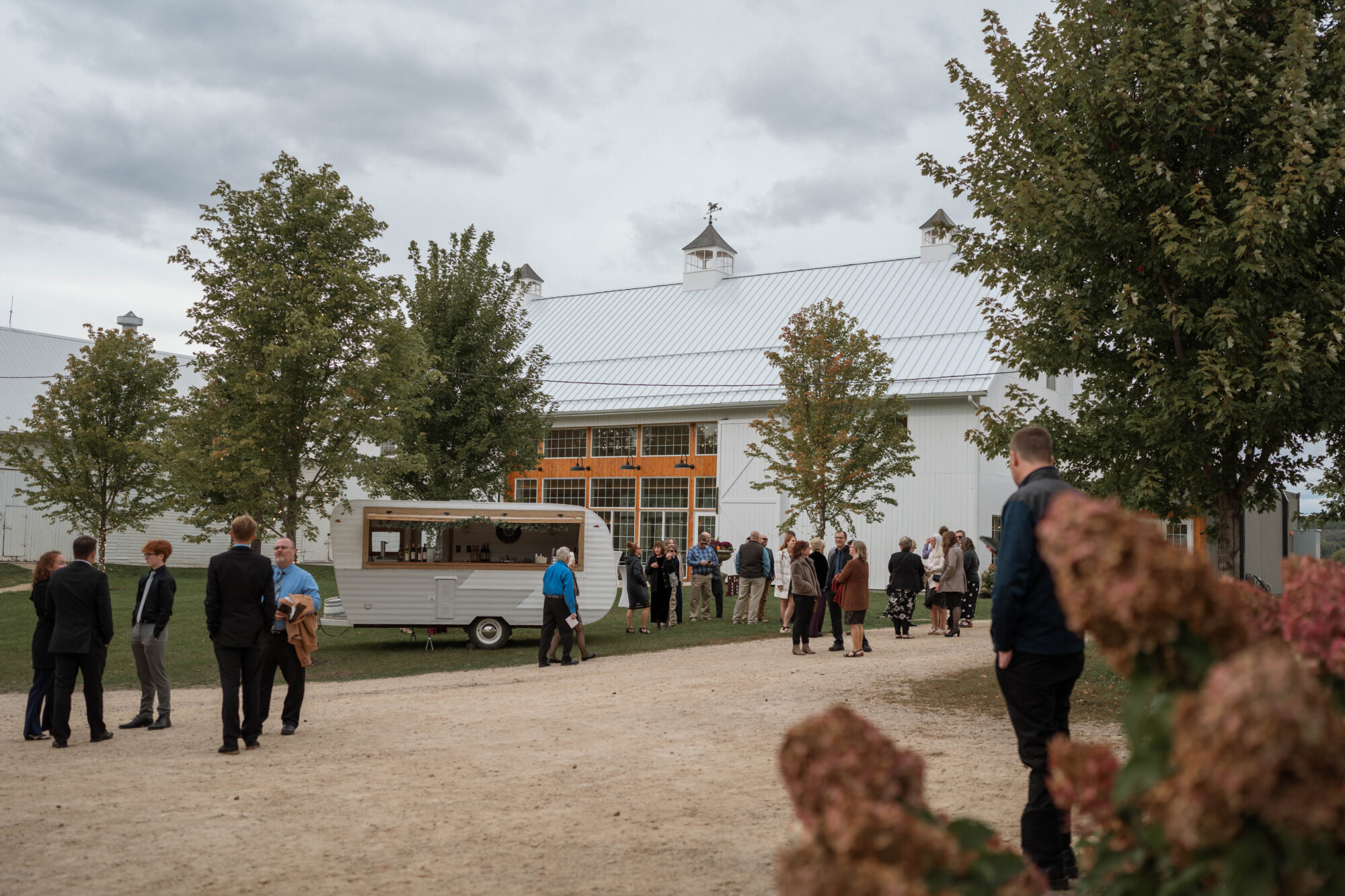 Wide shot of wedding venue and guests socializing during cocktail hour set at Willow Brooke Farm, in Red Wing, MN. 