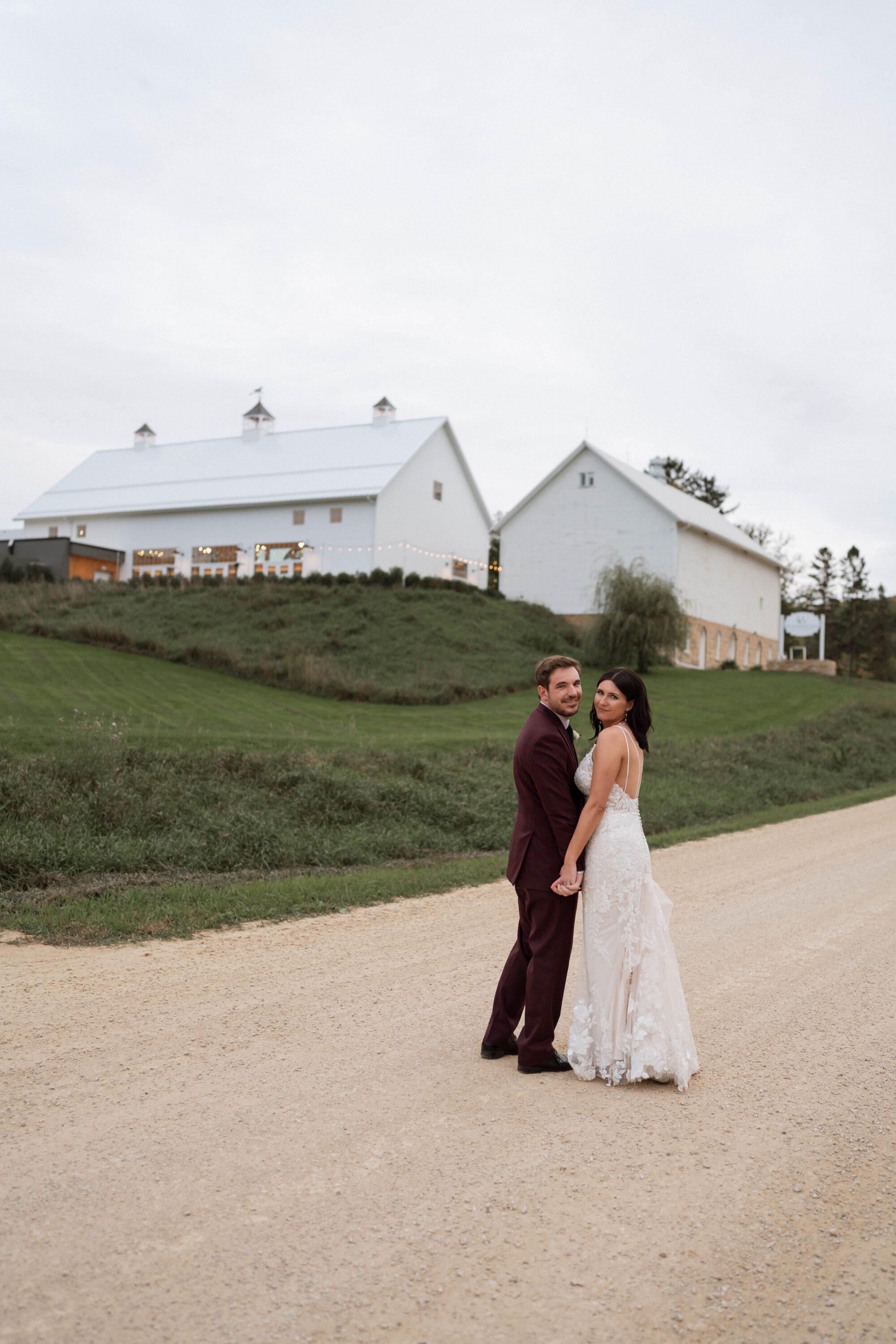 Couple at Willow Brooke farm, married and standing in front of the venue on a gravel road.