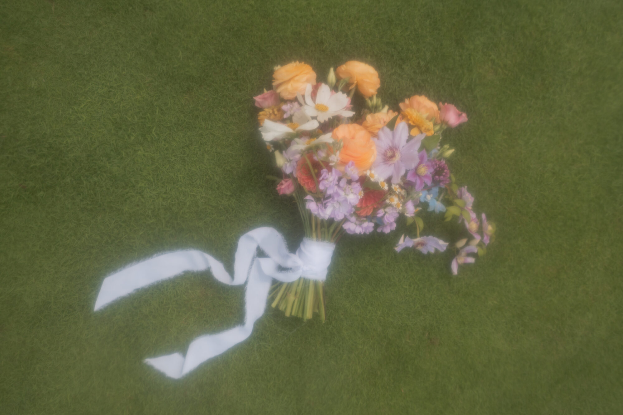 Film inspired shot of a colorful bridal bouquet on green grass.