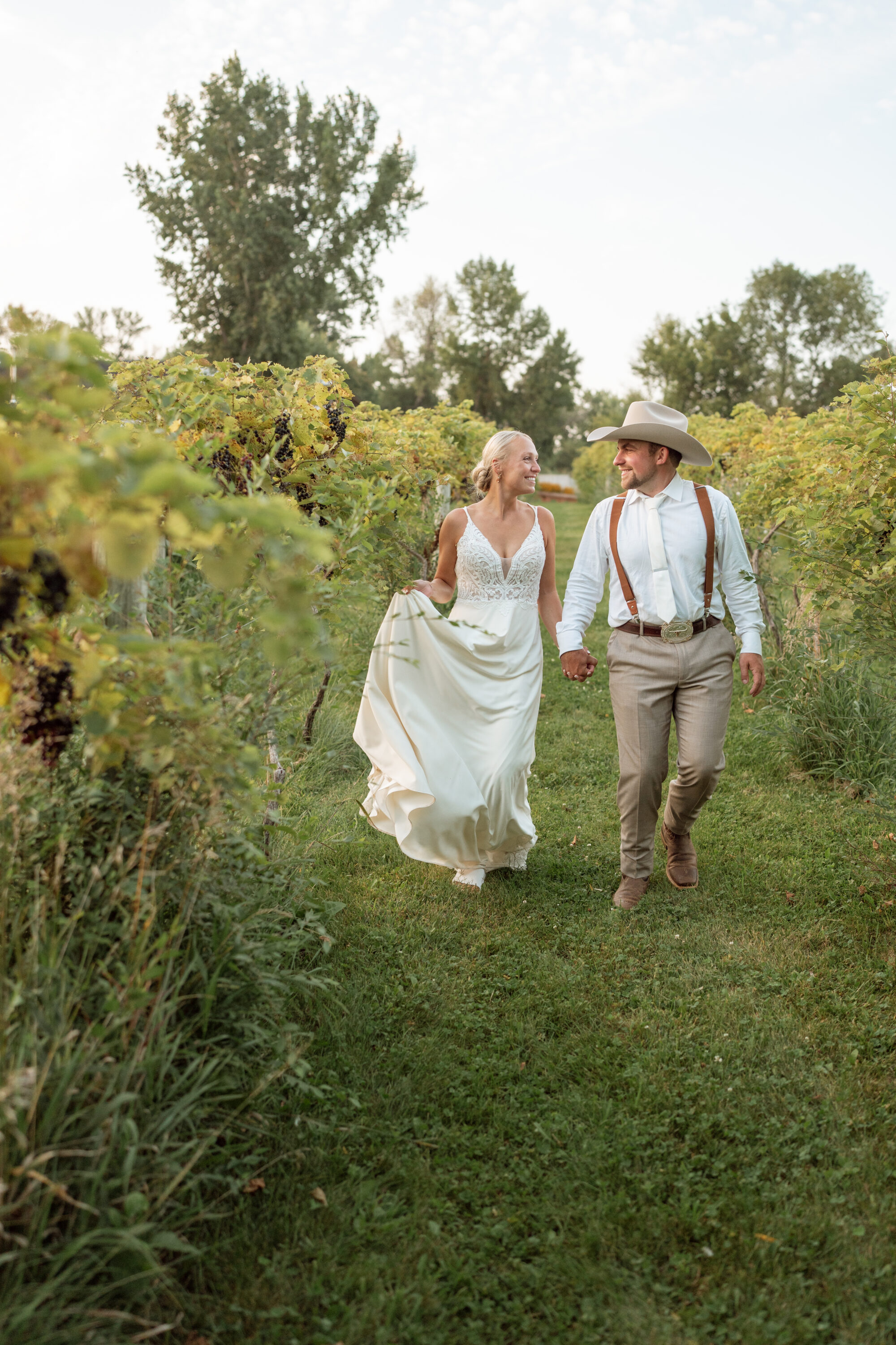 Bride and groom walking through a Minnesota vineyard.